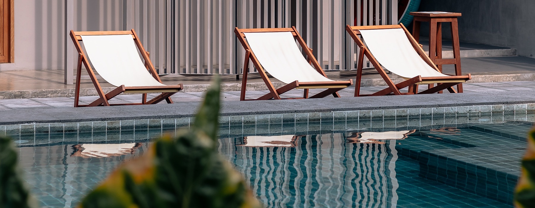 Serene swimming pool with modernly designed lounge chairs lining the side