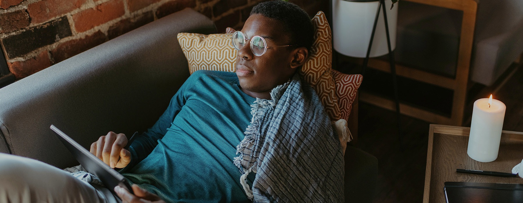 Man in glasses lounging on couch with his iPad